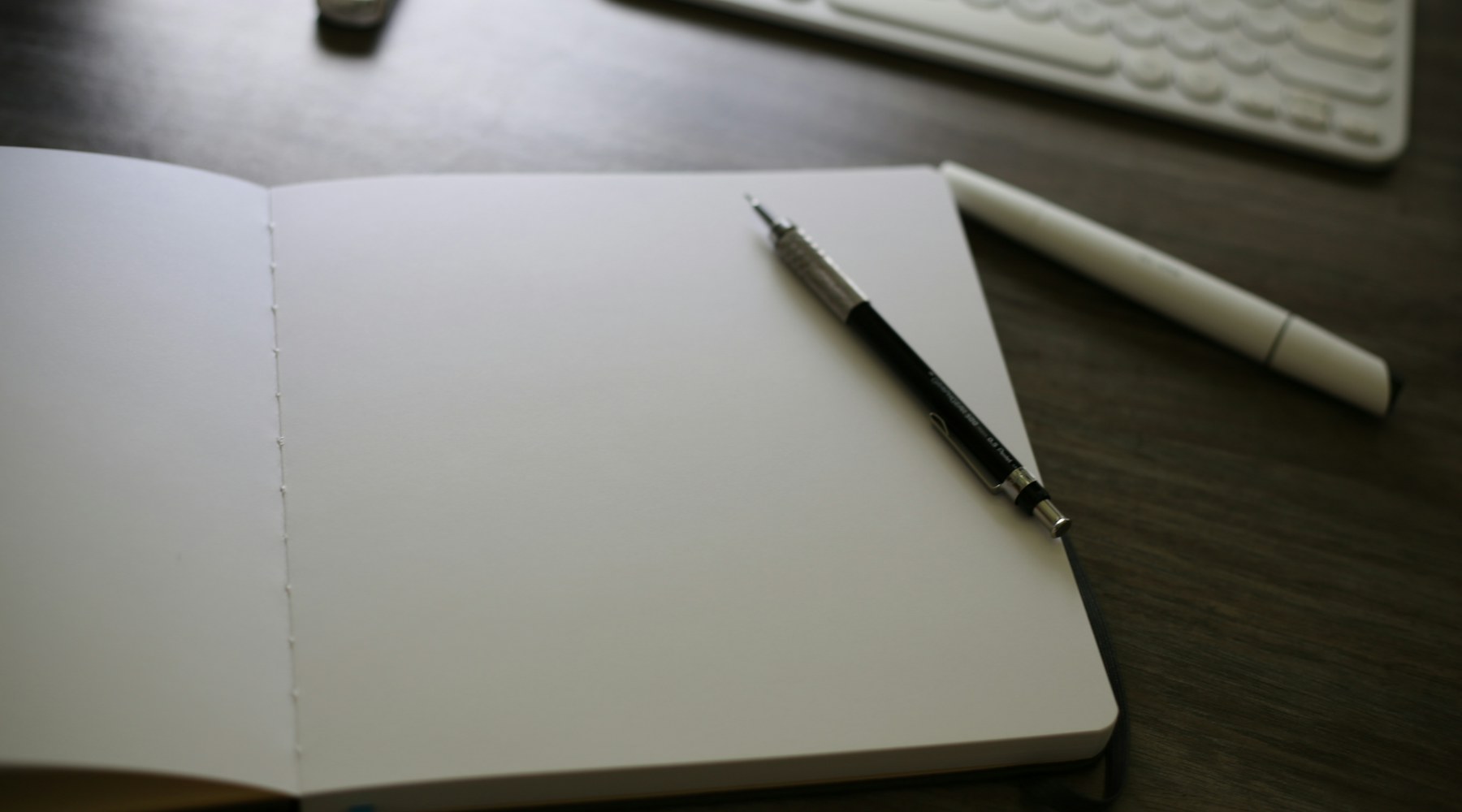 Open notebook and writing tools beside a keyboard